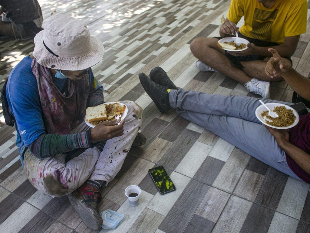 Los jóvenes que trabajan sobre el mural almuerzan juntos y conversan durante su descanso.