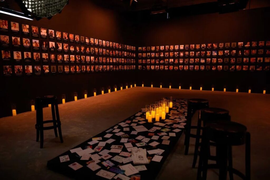 A memorial wall at When the Music Stopped Playing, displaying photographs of victims and survivors. | Photo courtesy of Naama Gal.