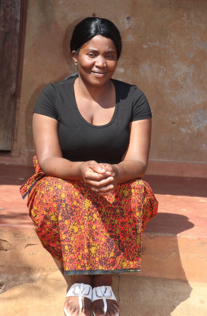 Maggie Chisoni sits outside her family home in Malawi after fleeing xenophobic violence in South Africa.