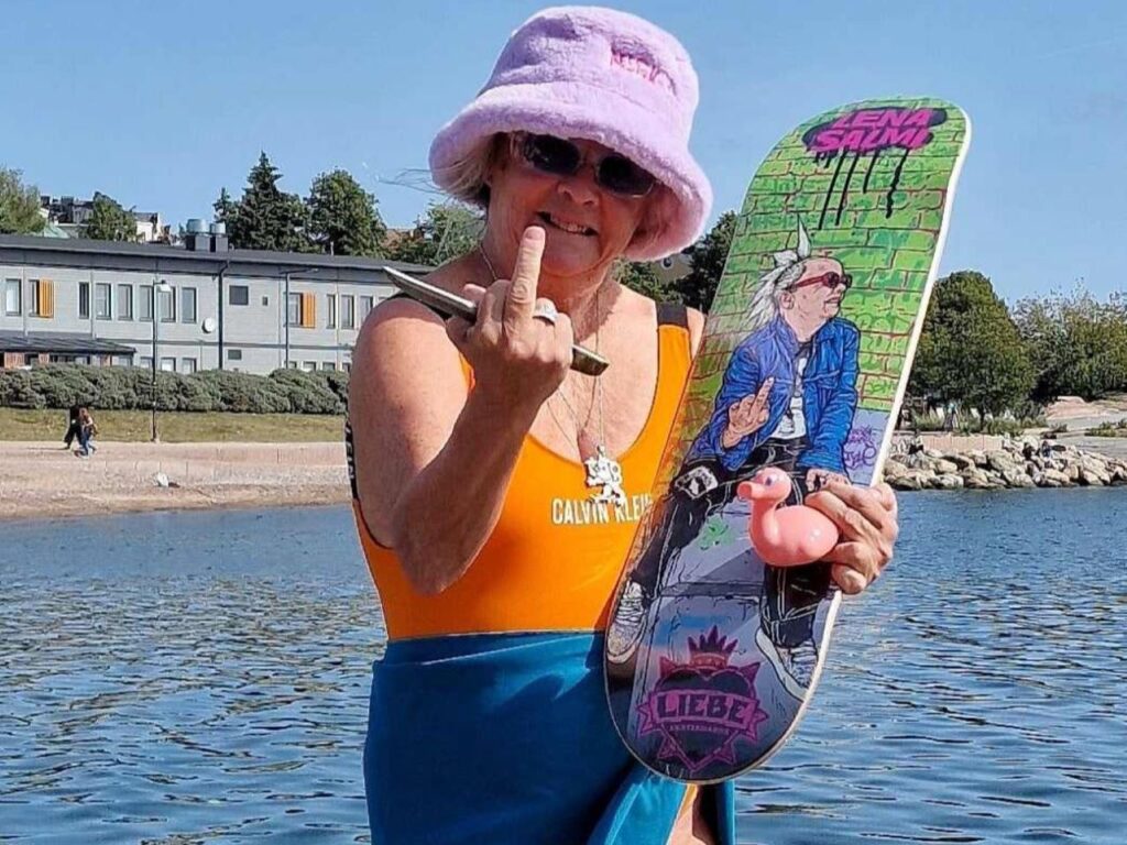 71 year old Lena of Finland holds the longboard that features her image. | Photo courtesy of Lena Salmi