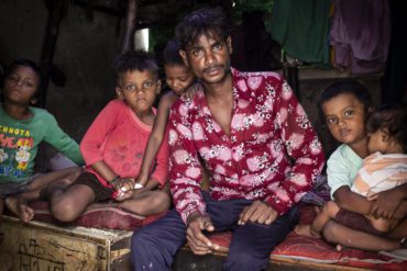 A "ragpicker" named Ashok sits inside his house with his five children in Nilothi, New Delhi