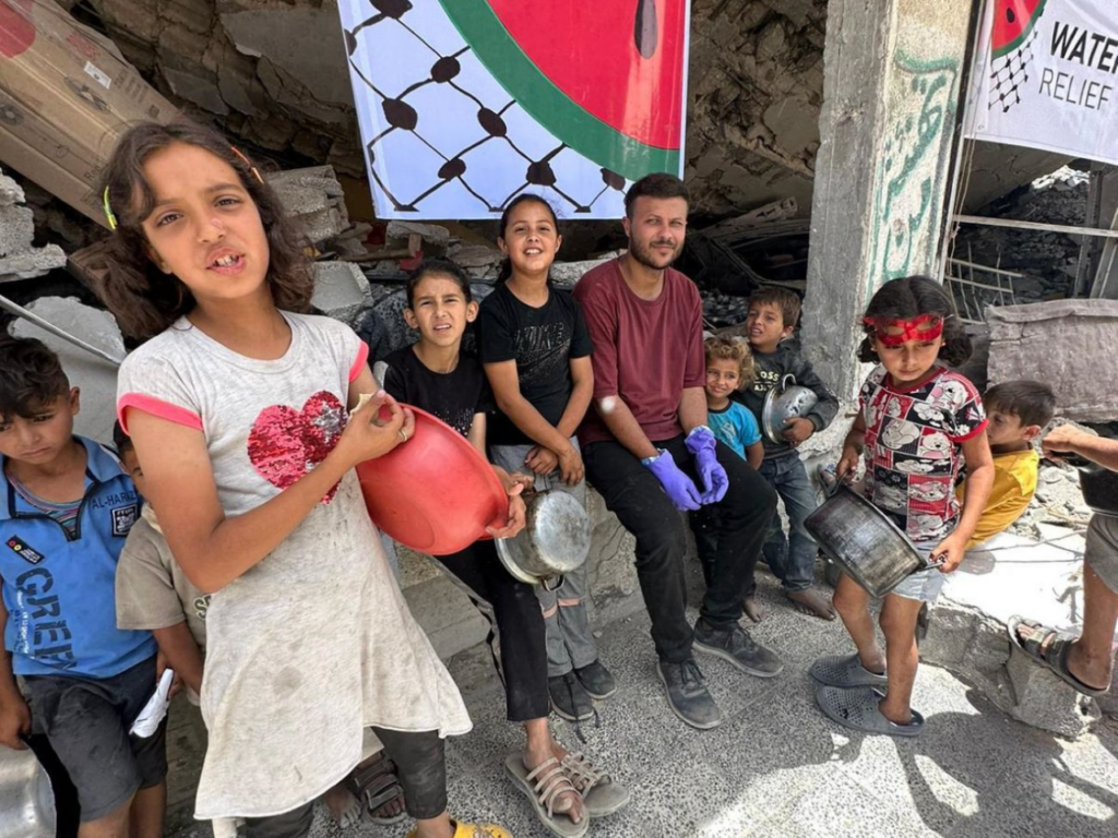 Hamada Shaqoura with children enjoying the meals he prepares in Gaza. | Photo courtesy of Hamada Shaqoura.