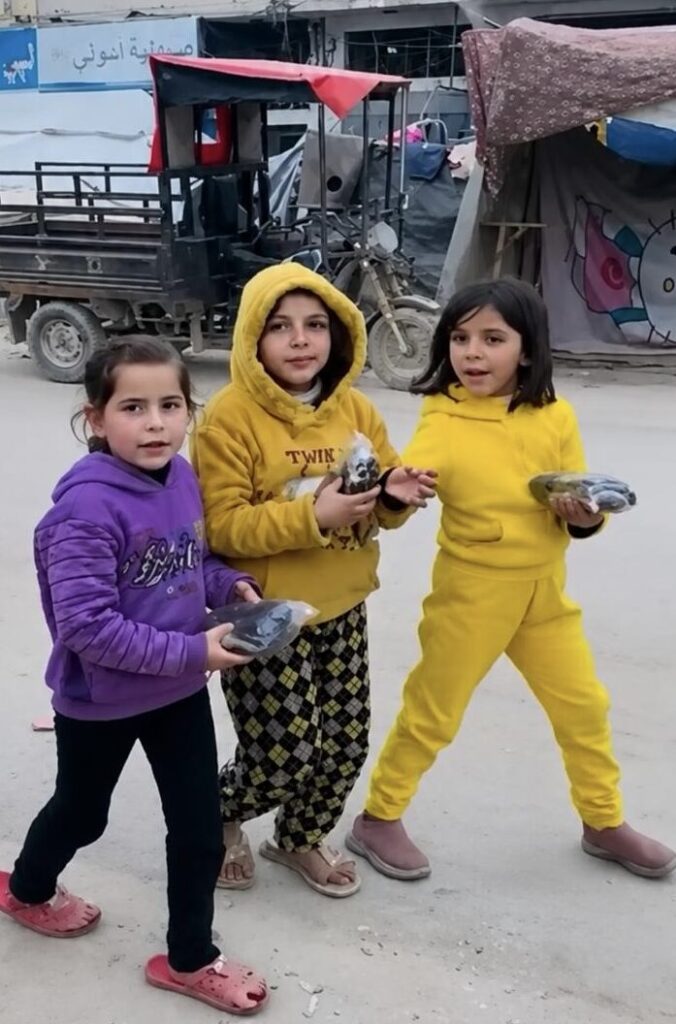 Noor Tawfiq caminando con otras dos niñas cerca de unos refugios transitorios.