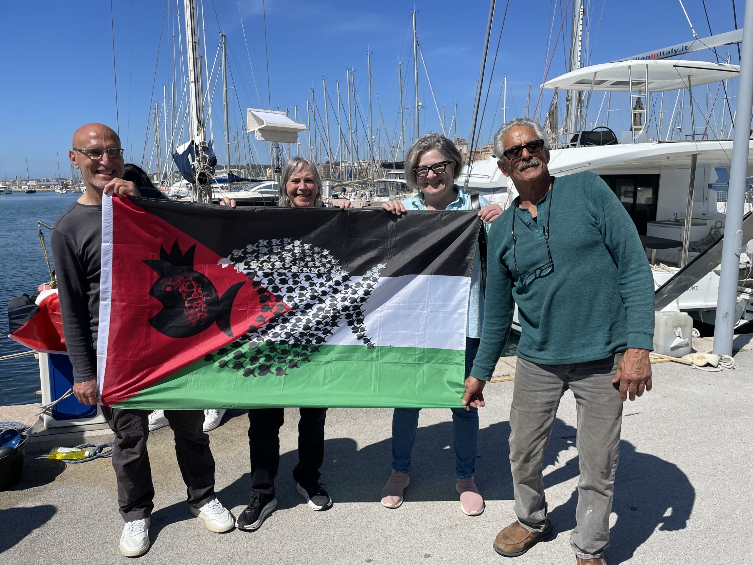 Gaza flotilla participants holding a Palestinian flag at a marina