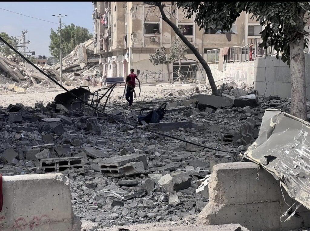 En el campamento de refugiados Nuseirat, en Gaza, una calle cubierta de escombros y unos edificios afectados por un ataque