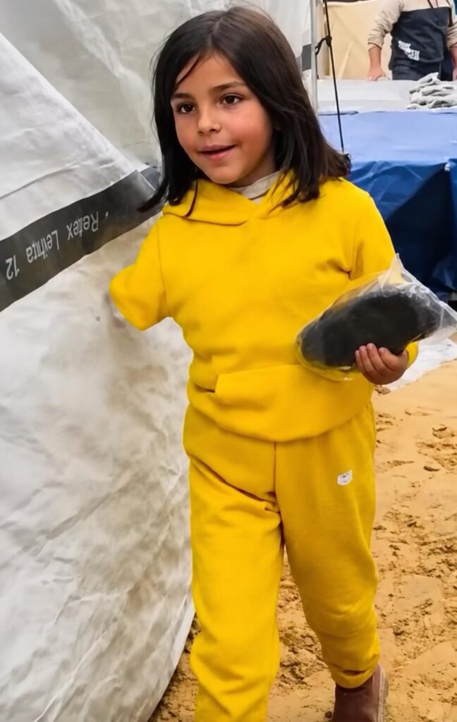 Noor Tawfiq, de pie, sostiene parte de su prótesis de brazo.