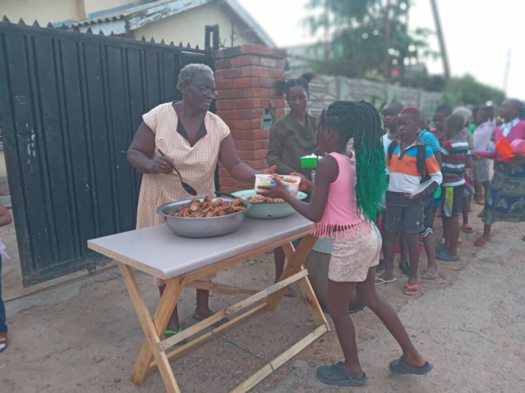 Children queue at Samantha's relief kitchen for food. | Photo courtesy of Kuchengetana Trust