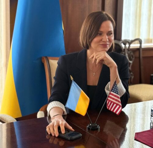 Ukrainian parliamentarian Anna Purtova seated at a conference table with Ukrainian and American flags in front of her.
