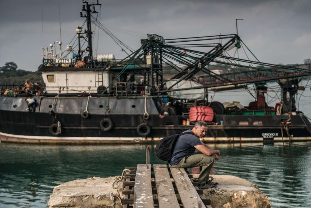Ian Urbina, Executive Director of The Outlaw Ocean Project, sits in front of a Greko vessel. | Photo courtesy of The Outlaw Ocean Project