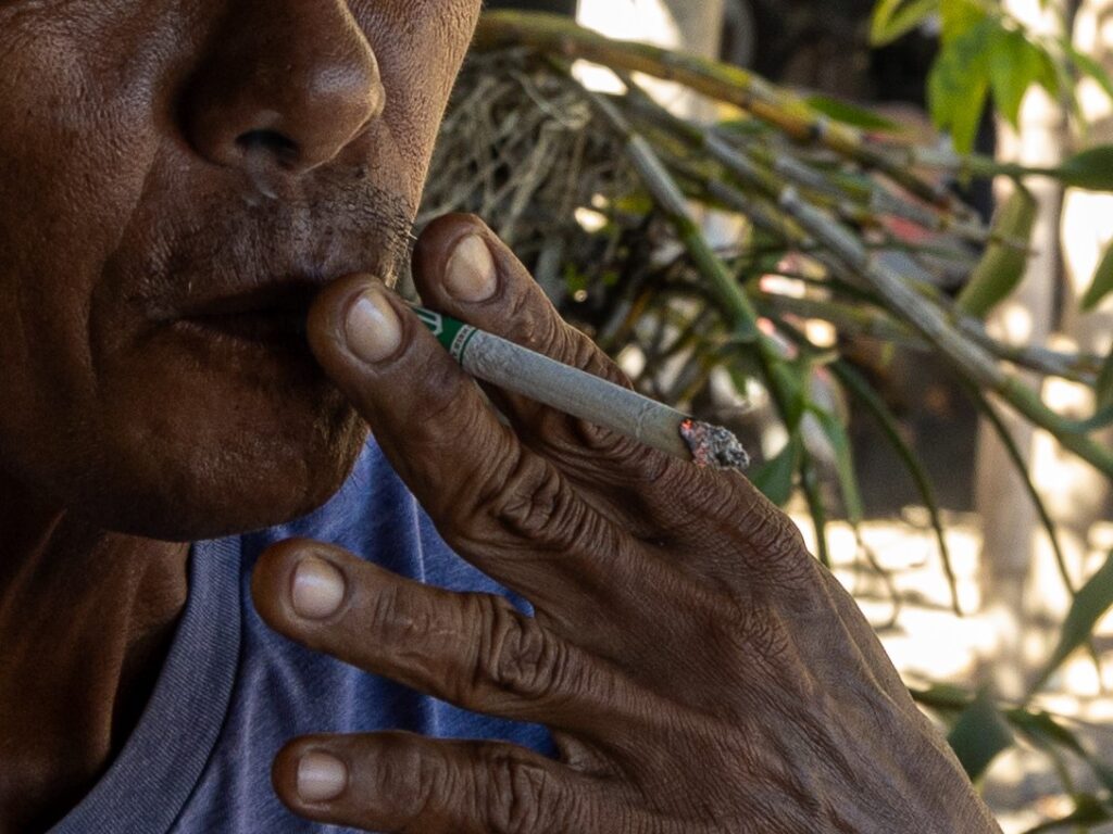 Wilifred, a Filipino tobacco farmer, lights a cigarette as a signal that he has finished planting for the day | Photo courtesy of Jose Monsieur Santos