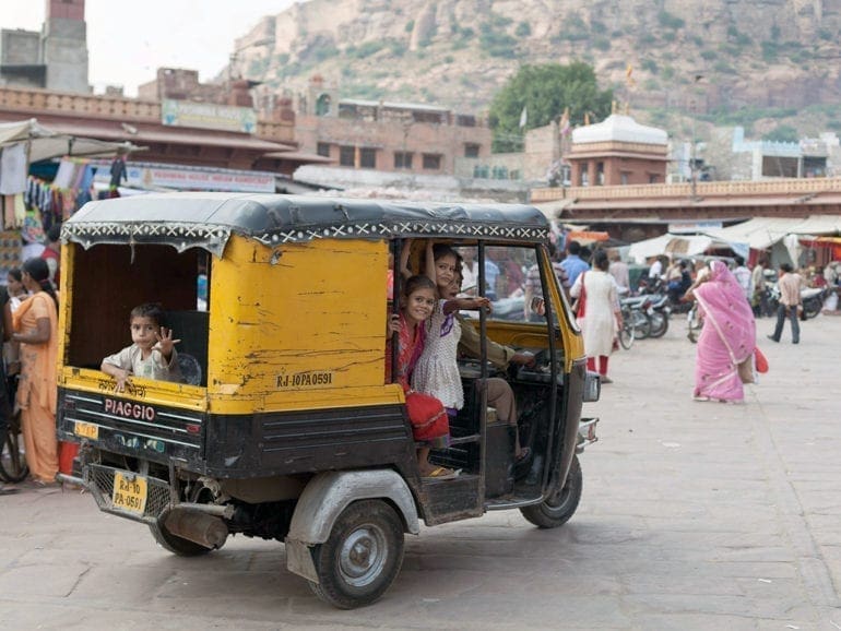Kids look out the open side of a tuktuk in Rajasthan, India.