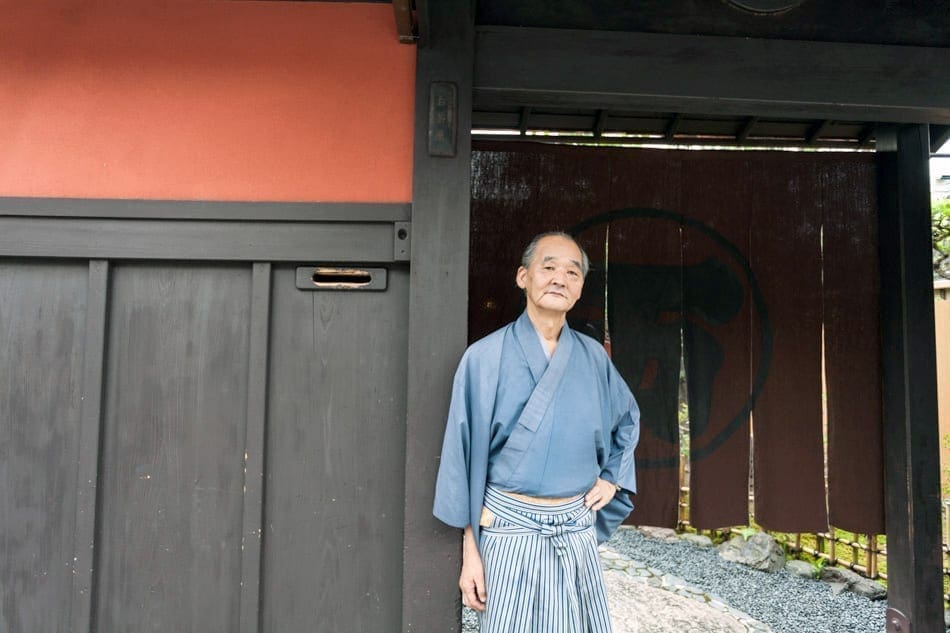 A man poses next to a doorway in a portrait.