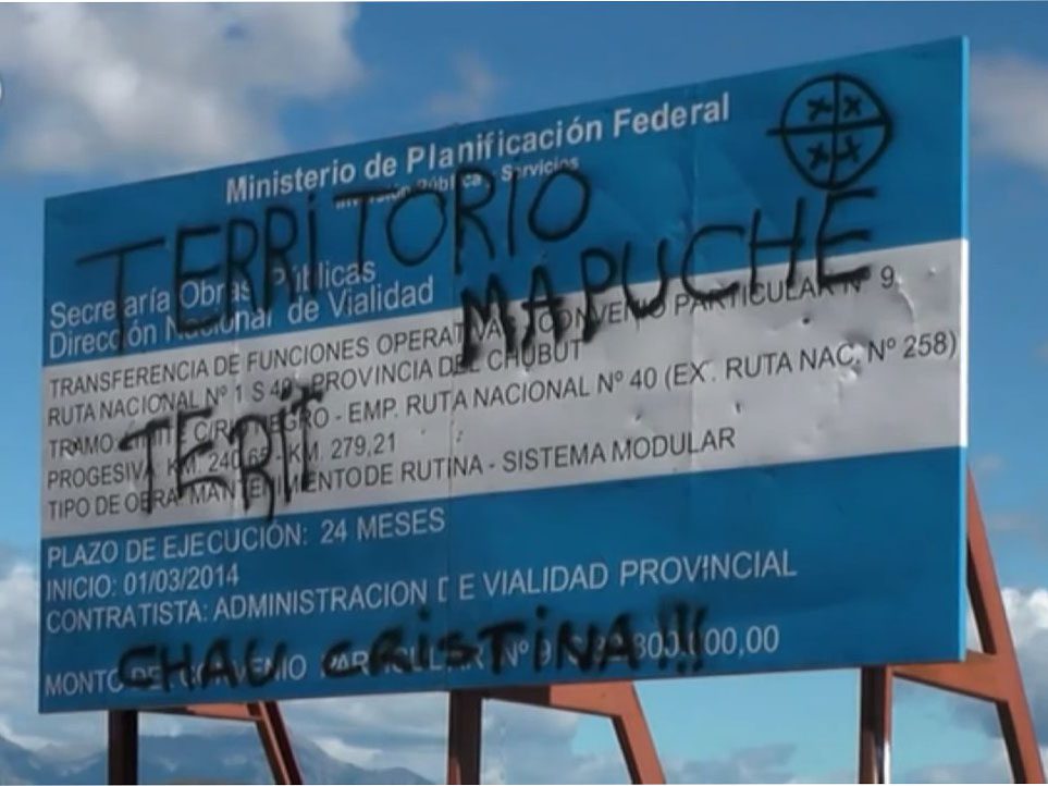 Near the disputed land a government sign in Argentina is spray painted with the message "Mapuche Territory"