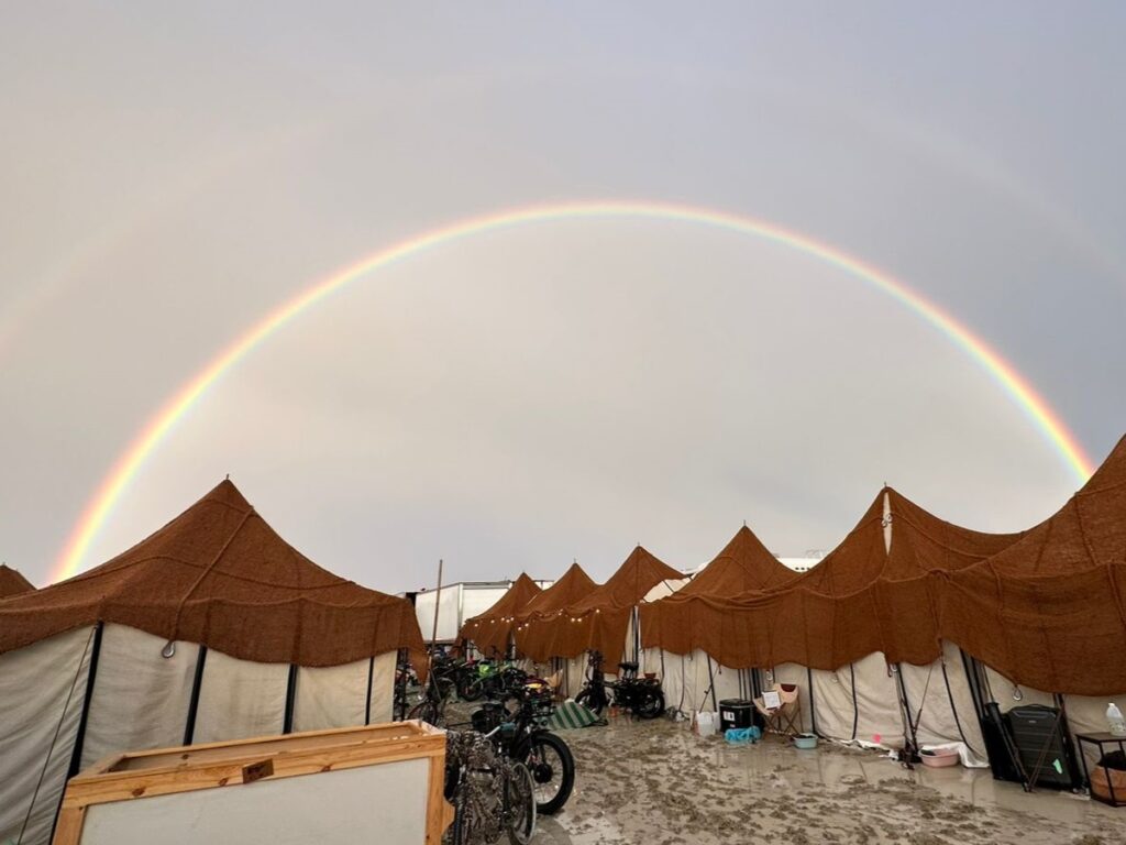 Amidst the muddy camp at the Burning Man event, a glorious rainbow appeared in the sky.