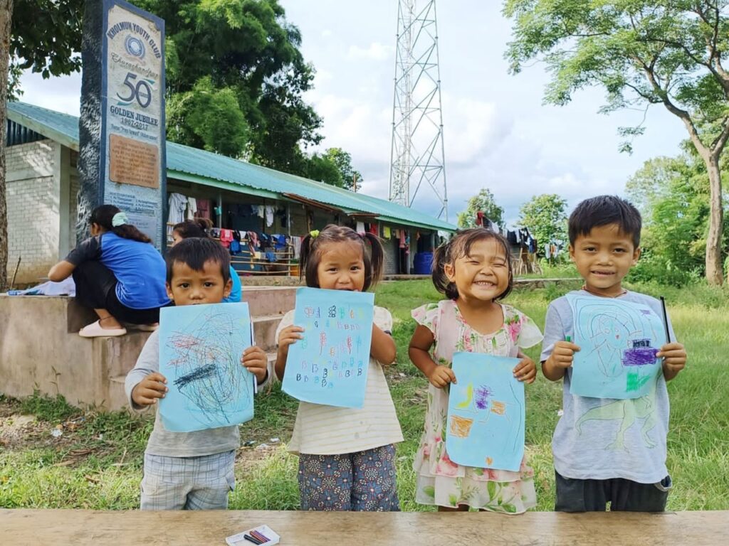 Four of the children at  the 
A drawing by Jamhoujil (L) is displayed along with his classmates. 