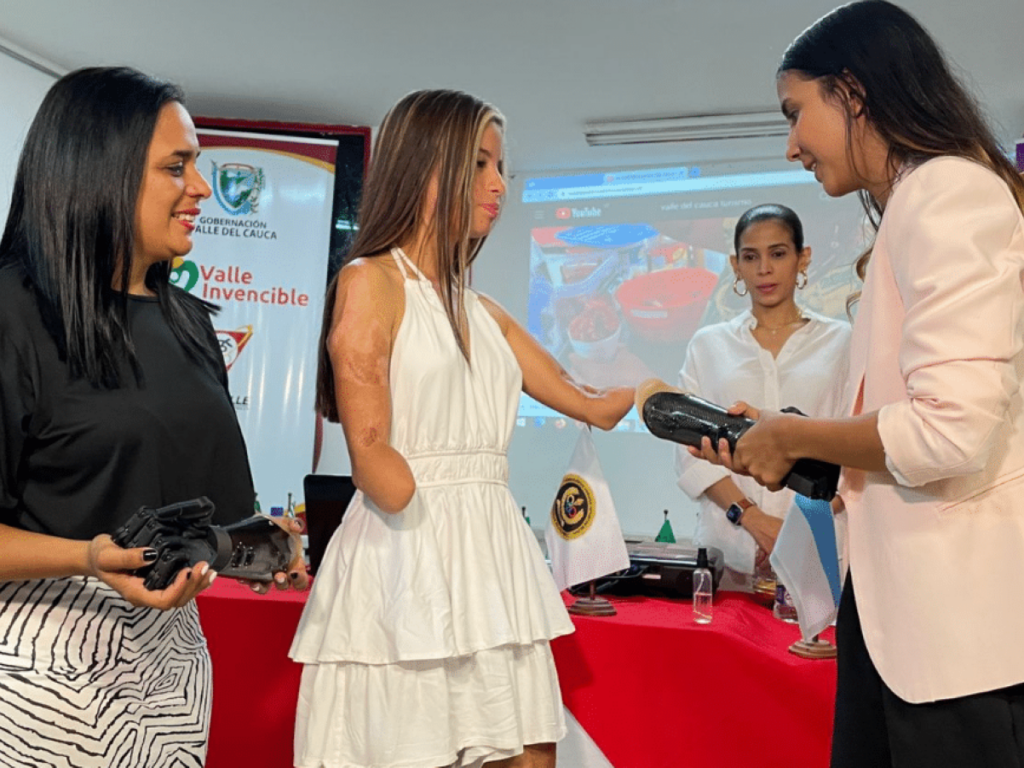 Karol Bastidas (center), the teen athlete in Colombia who lost her arms when she was electrocuted, received robotic, prosthetic hands at a special ceremony, flanked by her mother (left). | Photo courtesy of 