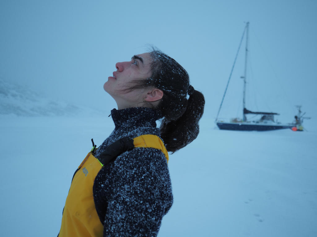 Tamara standing against a backdrop of snow and ice, her face lifted towards the sky as snow falls. | Photo courtesy of Tamara Klink.