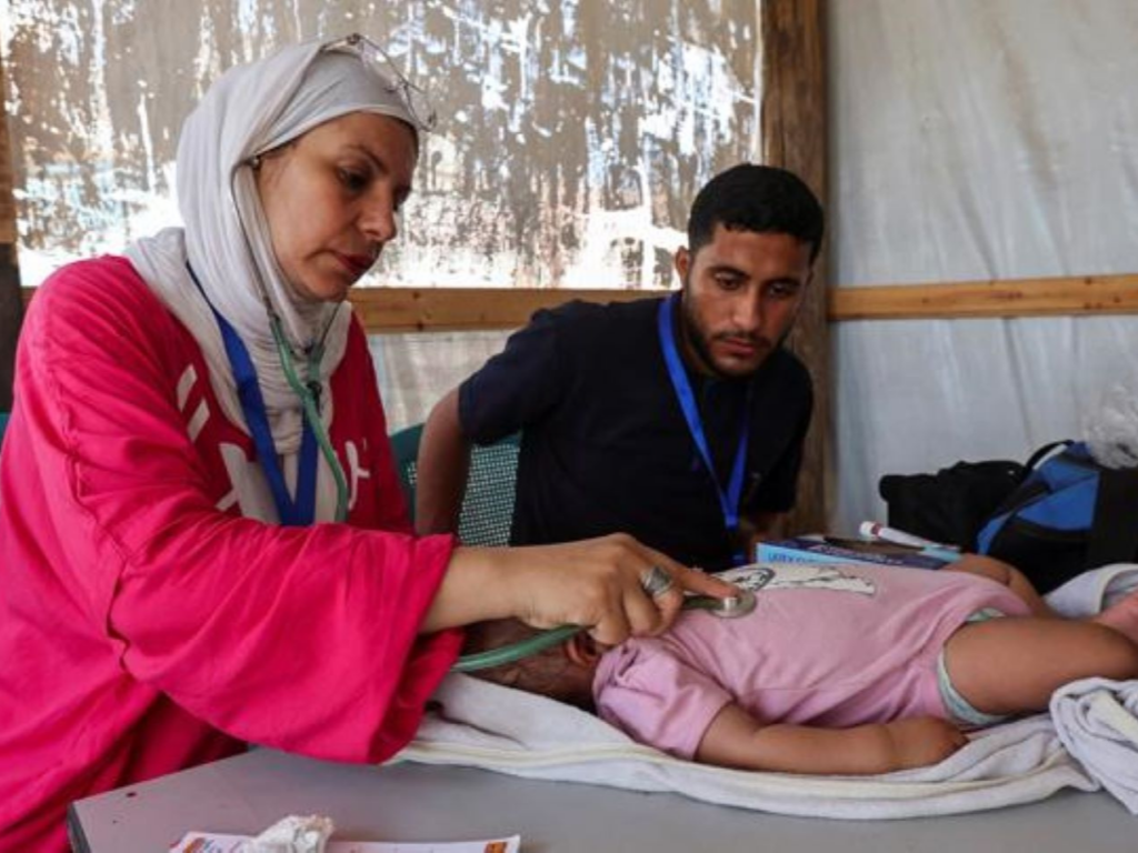 Dr. Lubna Al-Azaizeh, uses a stethoscope to examine a baby survivor lying on a table. | Photo courtesy of Dr. Lubna Al-Azaizeh.